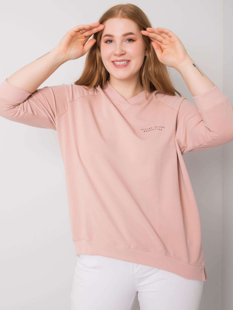 Powder pink sweatshirt of larger size with V-neck.